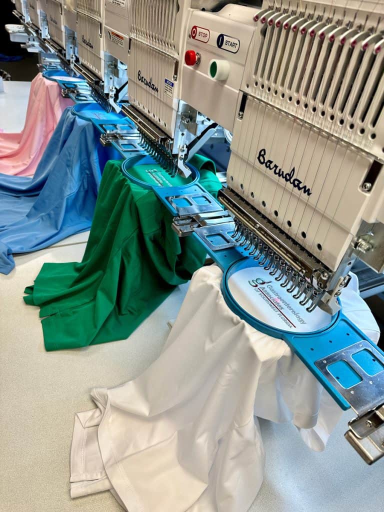 Industrial embroidery machine printing colorful designs on fabric in a professional setting.