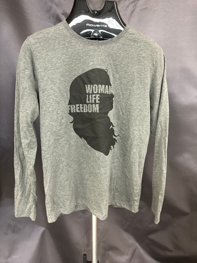 Empowering women's silhouette sweatshirt with "Woman Life Freedom" text in black on gray fabric.