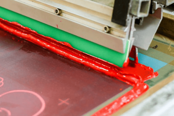 Industrial silk screen printing machine with red ink in Aworth, Georgia.